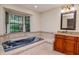 Bathroom with a marble soaking tub beneath the large window and cherry wood cabinets at 3428 Valley Ranch Dr, Lutz, FL 33548