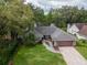 Beautiful home featuring a well-maintained lawn, mature trees, and a brick driveway leading to an attached two-car garage at 3428 Valley Ranch Dr, Lutz, FL 33548