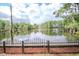 An idyllic lake view framed by trees, captured from a fenced and mulched backyard at 3428 Valley Ranch Dr, Lutz, FL 33548