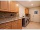 A laundry room featuring modern washer and dryer, tile flooring, granite countertops, and plenty of wood cabinet storage at 3428 Valley Ranch Dr, Lutz, FL 33548