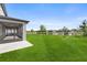 Expansive backyard featuring lush green grass, screened-in patio and a picturesque lake view at 34307 Radley Way, Wesley Chapel, FL 33545