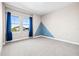 Bright bedroom with geometric accent wall, two windows, plush carpet, and blue curtains at 34307 Radley Way, Wesley Chapel, FL 33545