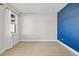 The room features wood floors, a bright blue accent wall, and a large window with sheer white curtains at 34307 Radley Way, Wesley Chapel, FL 33545