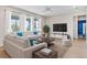 Bright living room with modern sofas, large windows, and a large television at 34307 Radley Way, Wesley Chapel, FL 33545