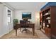 Cozy home office with wood desk, bookshelf, large window, and mountain landscape art at 34307 Radley Way, Wesley Chapel, FL 33545