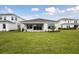 Home's back exterior featuring a covered patio, lush green lawn, and manicured landscaping at 3818 Farm Garden Ct, Lakewood Ranch, FL 34211