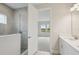 Bathroom with tiled shower behind glass wall and double vanity with a view to the carpeted bedroom at 3818 Farm Garden Ct, Lakewood Ranch, FL 34211