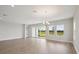 Bright and airy living room featuring wood floors, a modern chandelier, and sliding glass doors to the yard at 3818 Farm Garden Ct, Lakewood Ranch, FL 34211