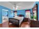 Comfortable bedroom with a ceiling fan, wood laminate floors, and ample natural light from two windows at 520 Canal Way, Oldsmar, FL 34677