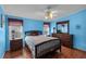 Cozy main bedroom featuring wood floors, ceiling fan, dresser, and natural light from two windows at 520 Canal Way, Oldsmar, FL 34677