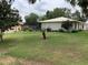 Backyard featuring a large green lawn, tall trees, and white house with screened-in pool at 6488 Robinswood Ave, Brooksville, FL 34602