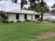 Charming single-story home with a metal roof, a well-manicured lawn, and a covered car in the driveway at 6488 Robinswood Ave, Brooksville, FL 34602
