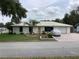 Charming single-story home with a metal roof, a well-manicured lawn, and a covered car in the driveway at 6488 Robinswood Ave, Brooksville, FL 34602