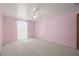 Spacious pink bedroom featuring a ceiling fan, neutral carpet, and a window letting in natural light at 6607 Larimer Dr, Tampa, FL 33615