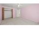 Pink bedroom view showing the closet with wooden bi-fold doors and doorway leading to other rooms at 6607 Larimer Dr, Tampa, FL 33615