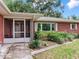 Close-up of a screened entry way, featuring a red brick exterior and tidy landscaping at 7216 N Mobley Rd, Odessa, FL 33556