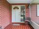 Inviting front porch with red-tiled floor, chair, and classic brick design at 7216 N Mobley Rd, Odessa, FL 33556