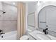 Modern bathroom featuring a tub with shower, granite countertops, and a sleek, arched mirror at 7614 Addison Ave, Bradenton, FL 34210