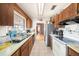 Galley kitchen featuring wood cabinets, white appliances, and an eat-in dining area at 8305 Palencia Dr, Port Richey, FL 34668