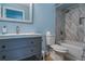 Bathroom with blue walls, gray vanity, toilet, and bathtub featuring elegant marble-style tile at 9481 Highland Oak Dr # 710, Tampa, FL 33647