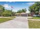 Charming ranch-style home with a well-manicured lawn, mature trees, and an American flag at 9981 58Th N St, Pinellas Park, FL 33782