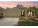 Charming single-story home with well-maintained landscaping, a two-car garage, and sunset backdrop at 10150 Heather Sound Dr, Tampa, FL 33647