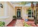 Inviting front entrance with brick walkway, decorative columns, and security system. The door has glass accent and transom window at 10150 Heather Sound Dr, Tampa, FL 33647