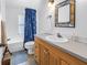 Bathroom with a blue shower curtain, white toilet, and oak vanity at 1038 Crescent Lake N Dr, St Petersburg, FL 33701