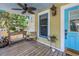 Inviting covered front porch with a ceiling fan, a table and chair set, and a blue front door at 1038 Crescent Lake N Dr, St Petersburg, FL 33701