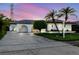 Charming single-story home with well-manicured lawn and mature palm trees at dusk at 10430 42Nd N St, Clearwater, FL 33762
