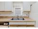 Close-up of the kitchen sink featuring white cabinets, a window with curtains, and a stainless steel sink at 10430 42Nd N St, Clearwater, FL 33762