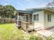 Backyard view of a home featuring a screened porch, small deck, and well-maintained lawn at 106 E Cedar St, Tarpon Springs, FL 34689