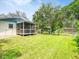 Backyard view of a home featuring a screened porch and a spacious, well-maintained lawn with trees at 106 E Cedar St, Tarpon Springs, FL 34689