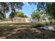View of the backyard featuring mature trees and a sunroom extension to the yellow house at 108 E Morgan St, Brandon, FL 33510