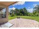 Covered patio with brick pavers overlooks a lush backyard with mature trees at 10837 Breaking Rocks Dr, Tampa, FL 33647
