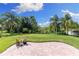 Brick-paved patio overlooks the green lawn and landscaped backyard with mature trees at 10837 Breaking Rocks Dr, Tampa, FL 33647