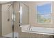 Bright bathroom featuring a glass-enclosed shower, soaking tub, and tiled accents at 10837 Breaking Rocks Dr, Tampa, FL 33647