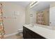Well-lit bathroom with a single vanity, framed mirror, and shower with a patterned curtain at 10837 Breaking Rocks Dr, Tampa, FL 33647