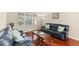 Cozy living room with leather sofas, wood coffee table, large window, and warm wood floors at 10837 Breaking Rocks Dr, Tampa, FL 33647