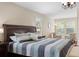 Comfortable primary bedroom features a king bed, chair sitting area, hardwood floors, and lots of windows at 10837 Breaking Rocks Dr, Tampa, FL 33647