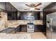Stylish kitchen with stainless steel appliances, a tiled backsplash, granite countertops, and dark wood cabinets at 1103 Old Mill Pond Rd, Palm Harbor, FL 34683