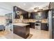Open concept kitchen with dark wood cabinetry, granite counters, stainless appliances, and adjacent living area with fireplace at 1103 Old Mill Pond Rd, Palm Harbor, FL 34683