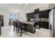 Modern kitchen with dark cabinetry, stainless steel appliances, a center island with seating, and bright adjacent dining area at 11917 Greenchop Pl, Riverview, FL 33579