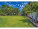 Large backyard with a lush green lawn, mature trees, and a privacy fence at 1212 Royal Oak Dr, Dunedin, FL 34698