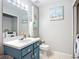 Bathroom with white toilet, sink, painted cabinet and decorative accents at 12426 Dawn Vista Dr, Riverview, FL 33578