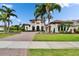 Stately two-story home featuring a red tile roof, balconies, and a lushly landscaped yard with mature palm trees at 16406 Chapman Crossing Dr, Lithia, FL 33547