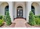 Grand entryway featuring double doors, decorative columns, and manicured shrubs along a brick-paved walkway at 16406 Chapman Crossing Dr, Lithia, FL 33547