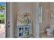 Hallway with a decorative cabinet, painting, and views into the half bathroom and outdoor area at 16406 Chapman Crossing Dr, Lithia, FL 33547