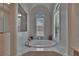 Bright main bathroom with a soaking tub featuring white plantation shutters in the arched window at 16406 Chapman Crossing Dr, Lithia, FL 33547