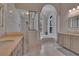 Bright main bathroom with dual sink vanity, walk-in shower, and soaking tub with arched window at 16406 Chapman Crossing Dr, Lithia, FL 33547